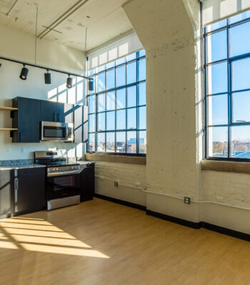 kraemer-design-group-kdg-detroit-piquette-flats-interior-apartments-kitchen-studio-lights-cityscape-brick-large-windows-multifamily-header-1200x800